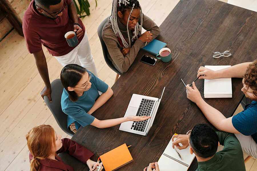 Mehrere Personen sitzen am Tisch und arbeiten am Laptop