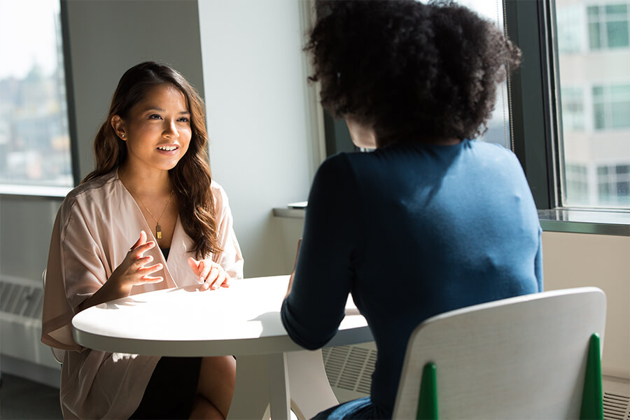 Zwei Frauen sitzen am Tisch und führen ein Gespräch
