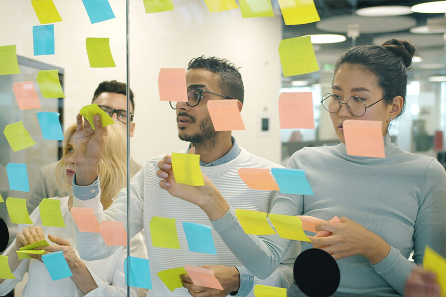 Personen kleben Post-its an eine Scheibe
