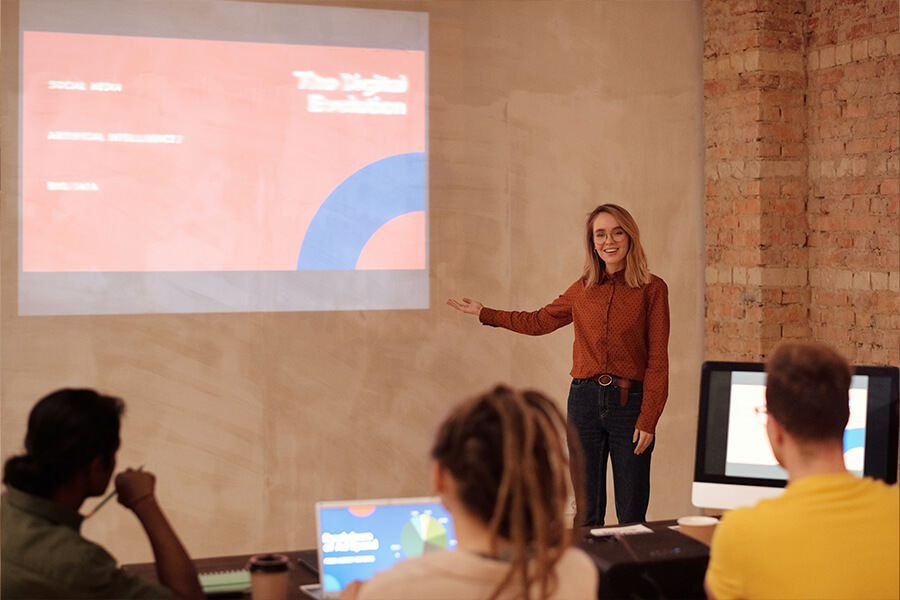 Frau steht an einem Beamer und hält ein Seminar
