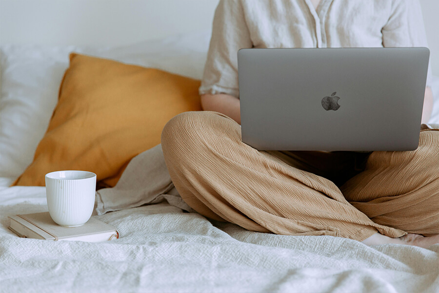 Person sitzt mir ihrem Laptop auf der Couch