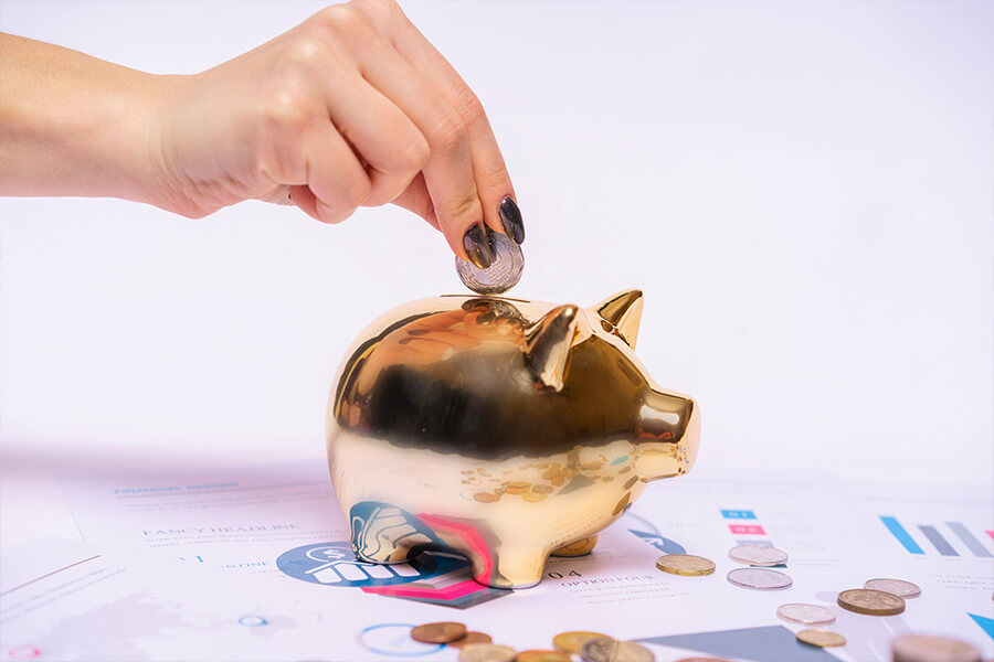 Person wirft Geld in ein Sparschwein