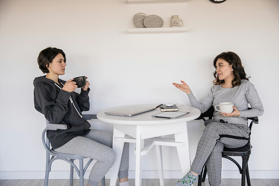 Zwei Frauen sitzen am Tisch und führen ein Gespräch
